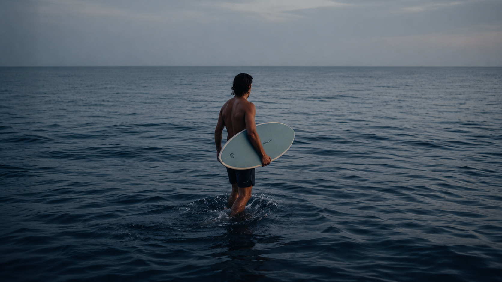 Surfer walking into dawn water